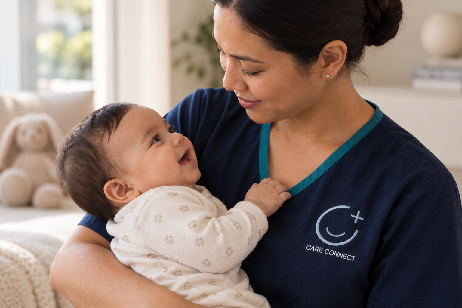 A Care Connect nurse in navy uniform smiling at a laughing baby in her arms
